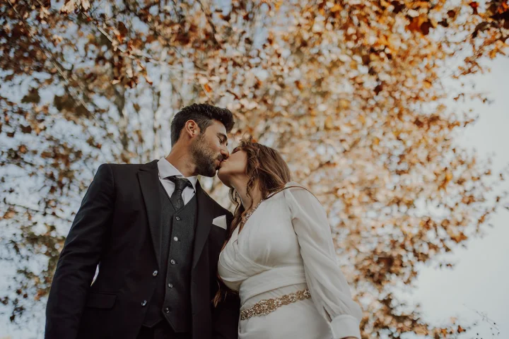 Coppia di sposi che si bacia sotto ad un albero in autunno a Cuneo. Matrimonio italiano, fotografo di matrimonio in provincia di Cuneo.