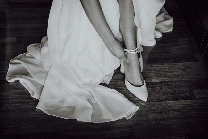 Dettaglio della sposa che allaccia la scarpa, bianco e nero. Fotografo di matrimonio a Cuneo.