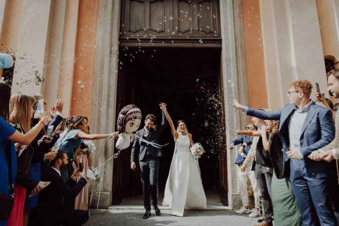 Sposi escono dalla chiesa, invitati che lanciano il riso, bolle di sapone. Matrimonio a Savigliano. Fotografo di matrimonio a Cuneo.